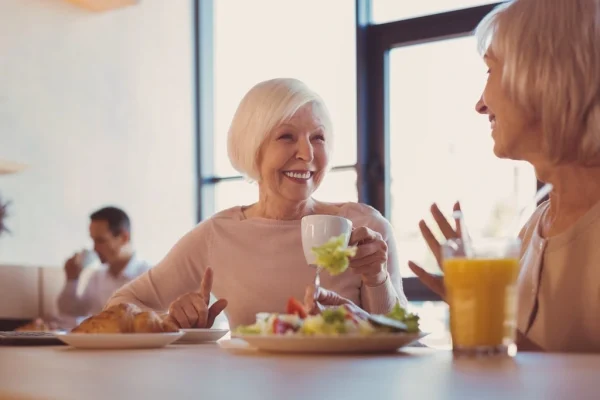 Two people having a conversation at a table. They are having a meal together.